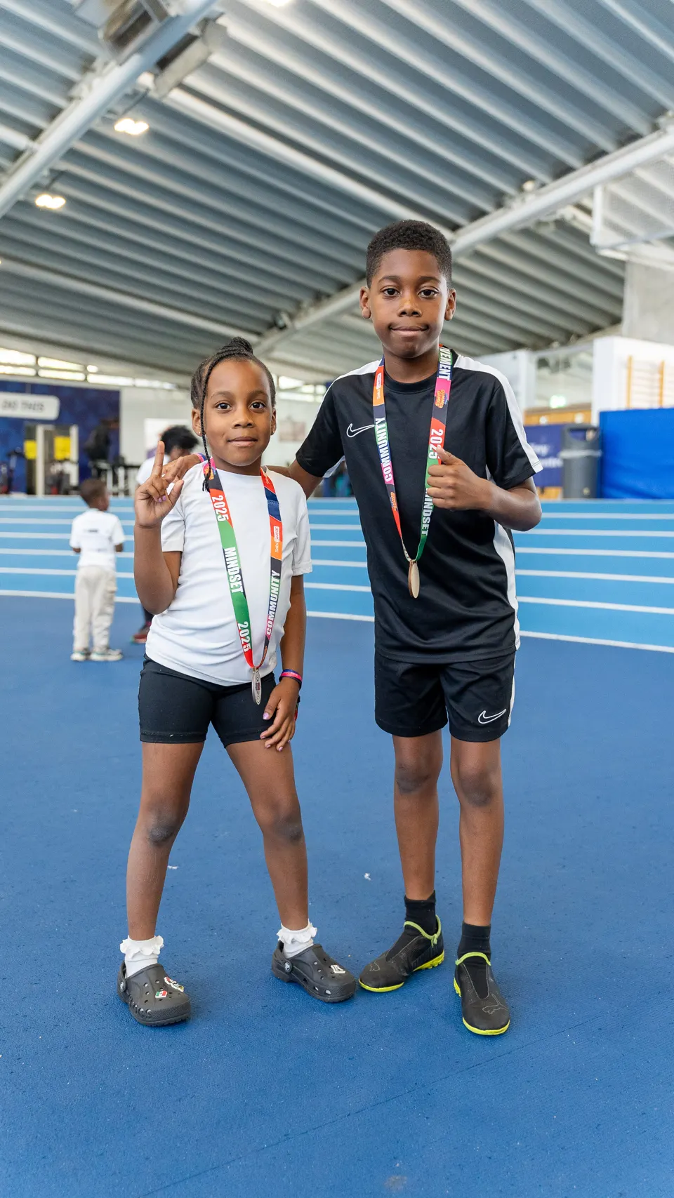 Two young members proudly wearing their finisher medals on the track