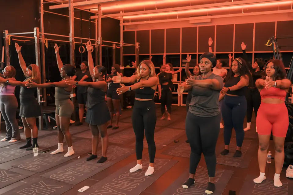 Rows of members mid-stretch at the Gymshark studio class, lit in red