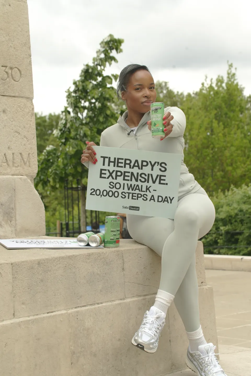 A member seated on a stone monument holding the Therapy's Expensive walking sign