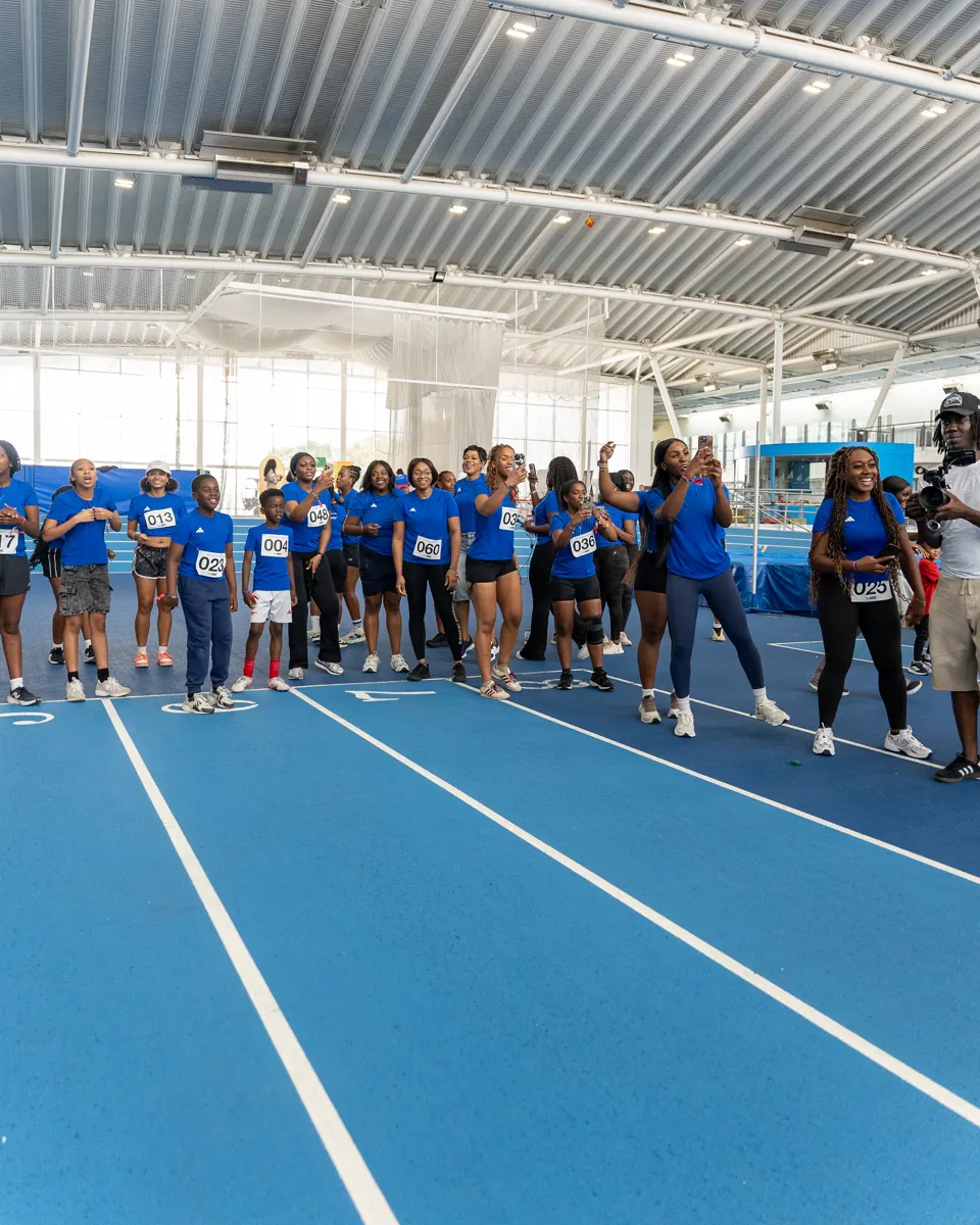 Members lined up mid-race at the Summer Games, one leaping through the air